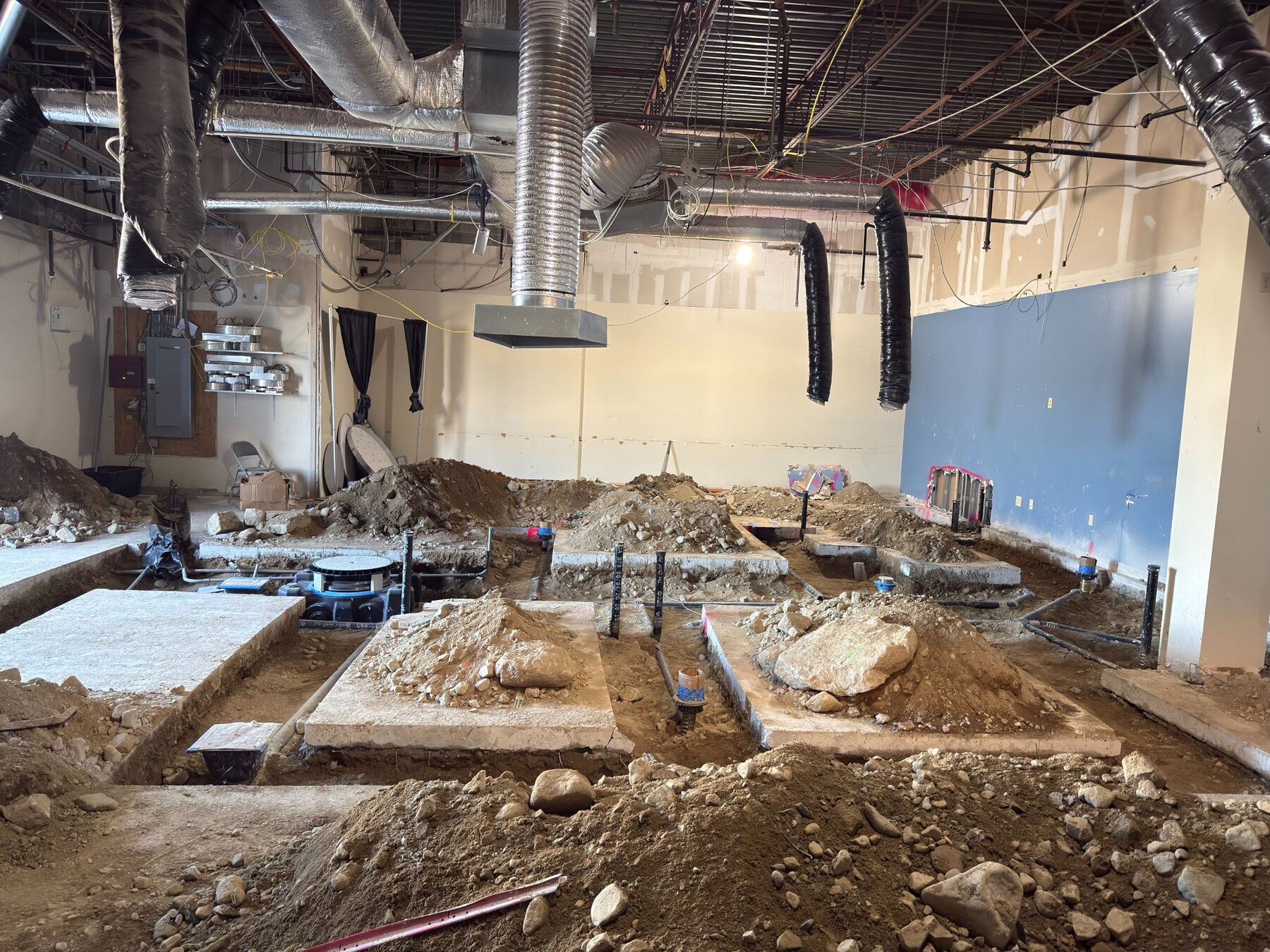 Underground plumbing and electrical rough-in work inside the restaurant space